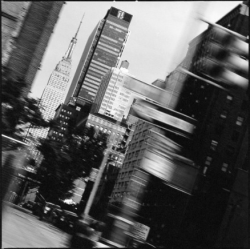 Black and white photo of city skyscrapers, including the Empire State Building, with blurred motion effect.