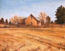 A solitary farmhouse stands in a dry, open field with sparse trees under a clear blue sky.