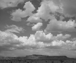 Flat-topped mesa under a sky filled with scattered clouds in a wide, open landscape.