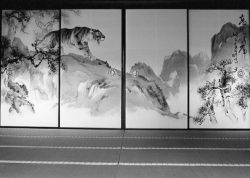 Black and white photo of traditional Japanese sliding doors with painted tiger, trees, mountains, and Japanese calligraphy.